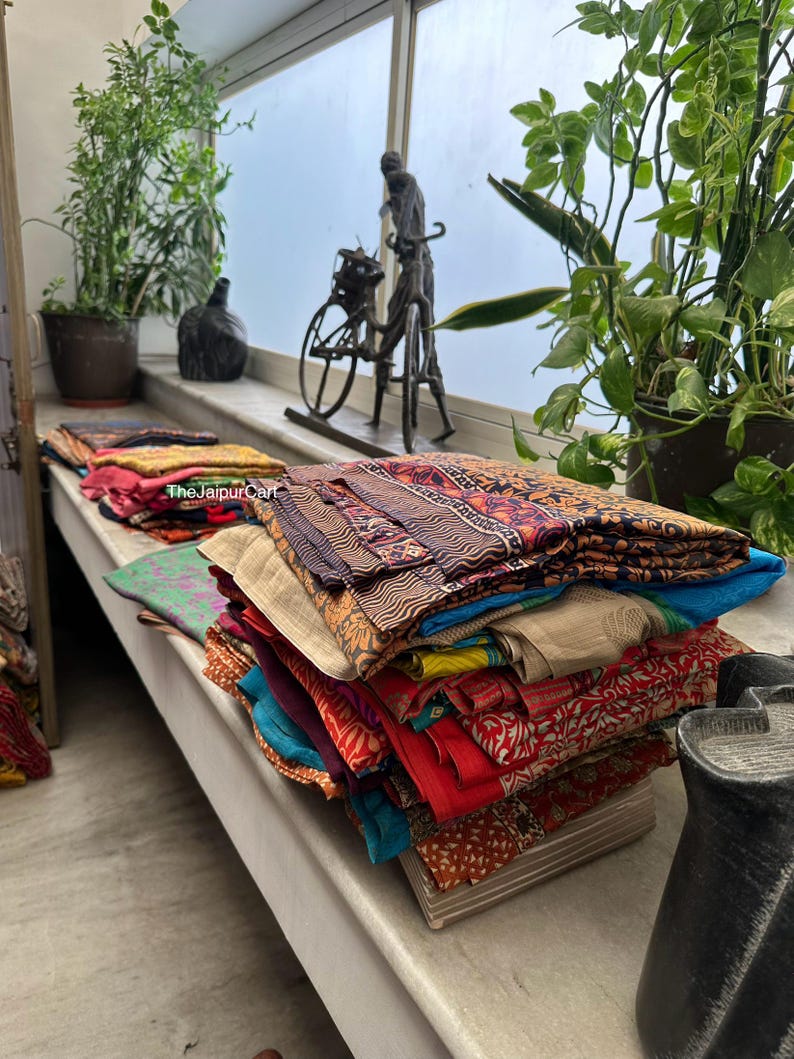 May include: A stack of colorful fabric squares with various patterns and textures. The fabric is folded neatly and arranged on a shelf. The fabric is likely for crafting or sewing projects.
