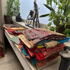 May include: A stack of colorful fabric squares with various patterns and textures. The fabric is folded neatly and arranged on a wooden surface. The fabric is likely for quilting or other craft projects.