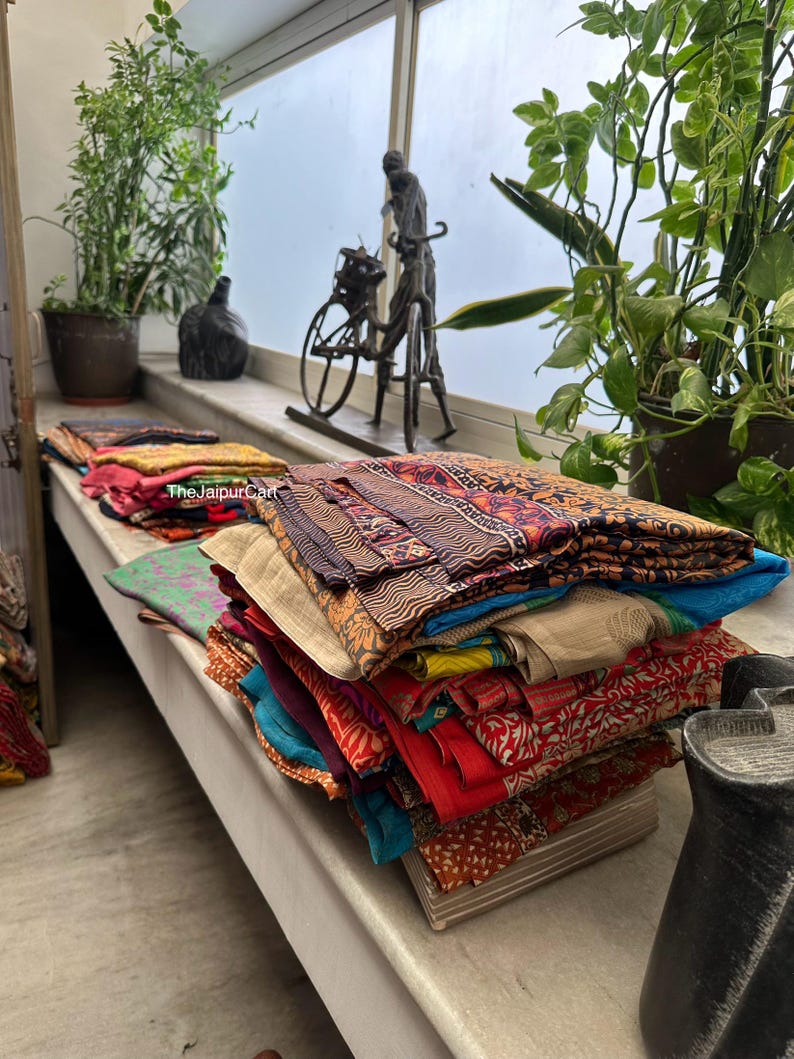 May include: A stack of colorful fabric squares with various patterns and textures. The fabric is folded neatly and arranged on a wooden surface. The fabric is likely for quilting or other craft projects.