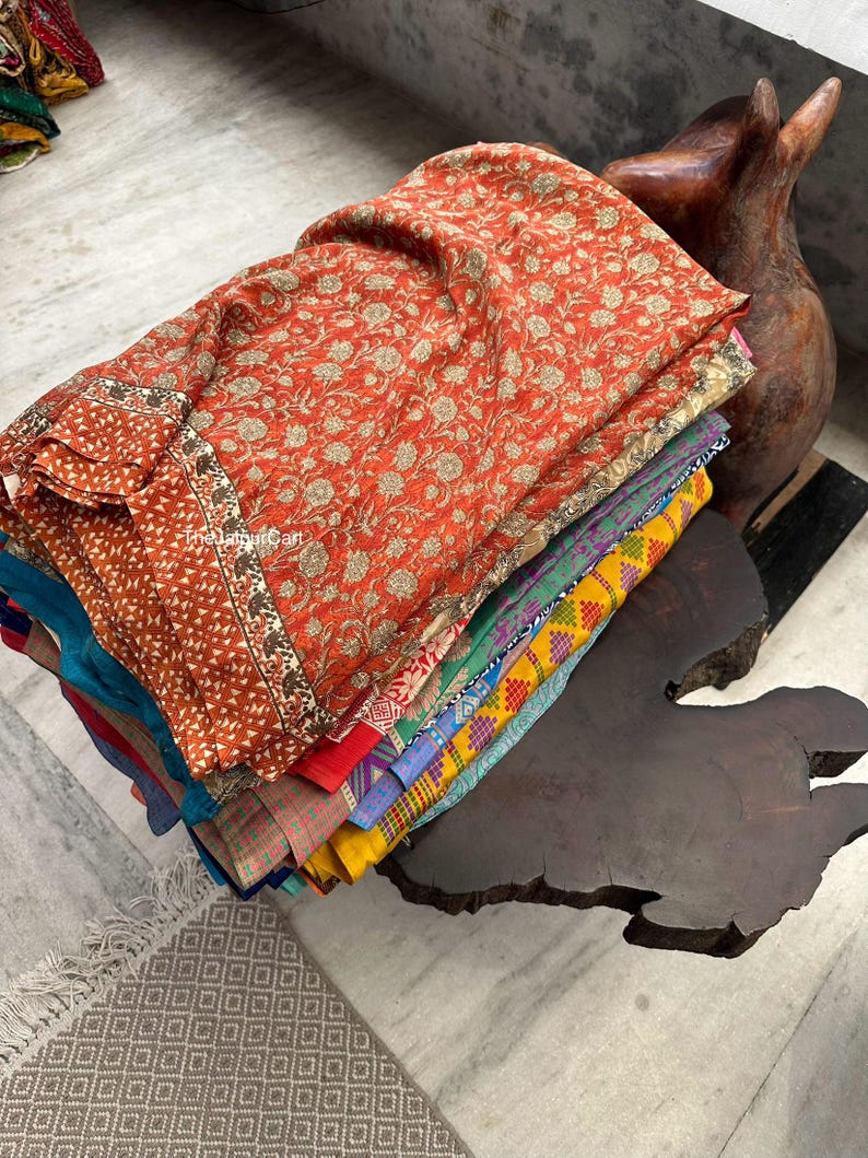 May include: A stack of colorful fabric squares with floral patterns, folded and arranged on a wooden surface. The fabric is likely used for quilting or crafting.