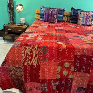 Puede incluir: Colcha kantha de patchwork rojo con una variedad de patrones y colores, incluyendo dorado, rosa y morado. La colcha está colocada sobre una cama con almohadas.