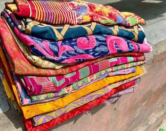 May include: A stack of colorful fabric scraps with various patterns, including floral, geometric, and abstract designs. The fabrics are folded neatly and arranged in a pile.