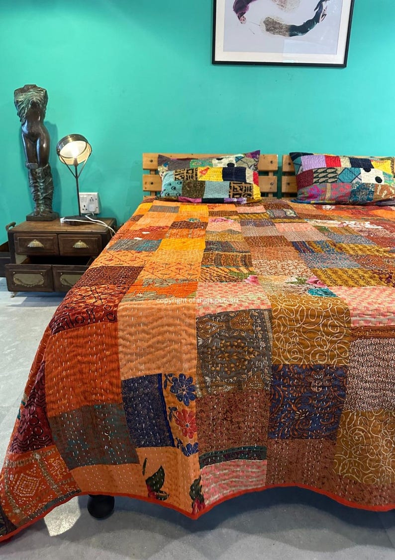 Puede incluir: Una colcha de retazos con una variedad de colores y patrones, incluyendo naranja, marr&oacute;n, azul y verde. La colcha est&aacute; hecha de diferentes telas y est&aacute; acolchada con una puntada corrida. La colcha est&aacute; en una cama con dos almohadas.
