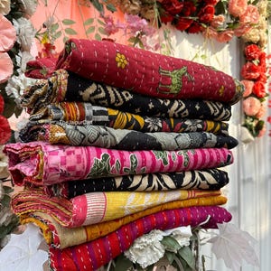 Peut inclure: Une pile de courtepointes kantha colorées avec différents motifs, notamment floraux, géométriques et animaliers. Les courtepointes sont en coton et sont cousues à la main. Les courtepointes sont disposées en pile sur un support en métal.