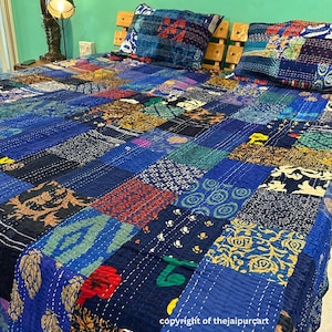 May include: A blue kantha quilt with a patchwork design featuring various colours and patterns. The quilt is made of cotton and is hand-stitched. It is a traditional Indian textile and is often used as a bedspread or throw.