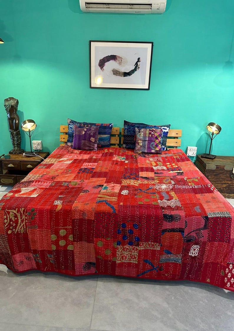 Puede incluir: Un edred&oacute;n rojo de patchwork con una variedad de patrones y colores, incluyendo rosa, azul y dorado. El edred&oacute;n est&aacute; colocado sobre una cama con dos almohadas y una cabecera de madera. La habitaci&oacute;n est&aacute; pintada de un color turquesa brillante.