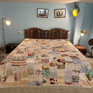 May include: A patchwork quilt featuring a mix of floral and geometric patterns in shades of pink, blue, green, and yellow. The quilt is displayed on a bed with a wooden headboard and a white bed skirt. The quilt is crafted from cotton and hand-stitched.
