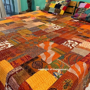 Könnte beinhalten: Eine Patchwork-Decke mit einer Vielzahl von Farben und Mustern, darunter Orange, Braun und Grün. Die Decke besteht aus verschiedenen Stoffen, die in einem zufälligen Muster zusammengenäht sind. Die Decke liegt auf einem Bett mit zwei Kissen.