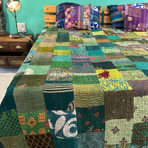 Könnte beinhalten: Eine Patchwork-Quiltdecke in Grün-, Türkis- und Olivtönen mit einer Vielzahl von gemusterten Stoffquadraten. Das Bett ist mit mehreren dekorativen Kissen in komplementären Farben geschmückt. Das Kopfteil ist aus Holz.