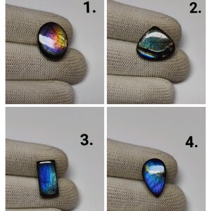 May include: Four polished labradorite gemstones labelled 1 to 4. Gemstone 1 is oval, 2 is triangular, 3 is rectangular, and 4 is teardrop-shaped. Each stone displays iridescent flashes of blue, purple, and gold against a dark base.