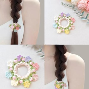 Puede incluir: Una goma para el pelo hecha a mano con un diseño floral de ganchillo. El accesorio para el cabello tiene una banda elástica rosa claro rodeada por un anillo de pequeñas flores de ganchillo de colores en tonos pastel de rosa, amarillo, azul y morado. La goma se muestra en uso.
