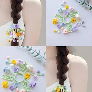 Könnte beinhalten: Häkel-Haaraccessoires mit farbenfrohen Blumenmustern. Die Accessoires umfassen ein grünes Gummiband, das mit gelben, blauen, rosa und lila Blumen verziert ist. Das Bild zeigt die Accessoires an einem Zopf und auf einer weißen Oberfläche.