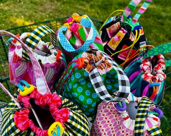 Puede incluir: Una colección de pequeñas bolsas de tela con cordón ajustable que presentan varios patrones coloridos, incluyendo caras sonrientes verdes, cuadros vichy en blanco y negro, formas geométricas rosas y estampados florales, cada una con asa.