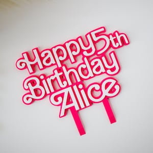 May include: Pink and white cake topper with the text "Happy 5th Birthday Alice".