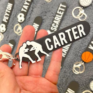 May include: Black and white wrestling keychain with the name "CARTER" on a black tag. The keychain is attached to a silver ring.