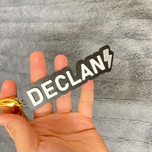 May include: A black keychain with a white lightning bolt and the name "DECLAN" in white letters.
