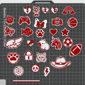 Selection of cute red and white acrylic-style charm add-ons for personalized keychains, displayed on a grid background. Charm options include fairy silhouette, bows, rainbow, rose, butterfly, gaming controller, camera, basketball, fish, paw prints, hearts, stars, wing, bell, hippo, unicorn, soccer ball, football, cat face, tiger paw, cowboy hat, panda, lightning bolt, orange slice, and lock charm. Kawaii cartoon style charms for custom sports, animal, gaming, and aesthetic keychains.