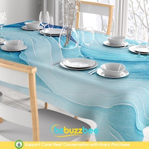 May include: A blue and white tablecloth with a wavy pattern. The tablecloth is set with white plates, bowls, and glasses. The text "Support Coral Reef Conservation with Every Purchase" is printed on the tablecloth.