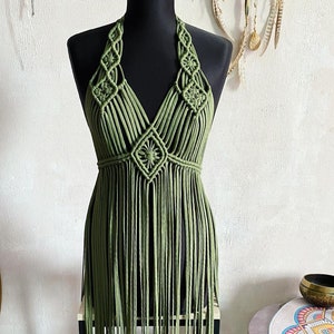 以下が含まれることがあります： フリンジが付いた緑色のクロシェのホルターネックトップ。トップはマクラメの手法で作られており、幾何学的なパターンがあります。