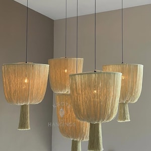 Puede incluir: Cinco lámparas colgantes con pantallas tejidas beige y una base en forma de borla. Las luces cuelgan de cables negros, iluminando un brillo cálido. Las lámparas están suspendidas del techo, creando una disposición de iluminación moderna y elegante.