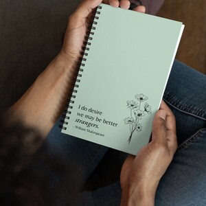 May include: A light green spiral bound notebook featuring a quote from William Shakespeare: "I do desire we may be better strangers." The quote is printed in black text and is accompanied by a black line drawing of a bouquet of flowers.