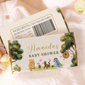 May include: A white chocolate bar wrapper with a Winnie the Pooh theme. The wrapper features illustrations of Winnie the Pooh, Piglet, Tigger, and Eeyore. The text "Amanda's Baby Shower" is printed in gold lettering.