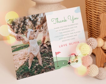 Pode incluir: Um cartão de agradecimento com uma foto de uma menina pequena com um vestido branco caminhando na grama. O cartão tem uma ilustração de um carrinho de golfe verde e rosa e o texto "Obrigado" e "Com amor Olivia".