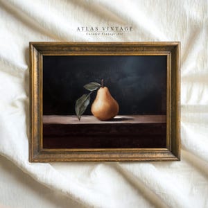 May include: A framed still life painting of a pear with two leaves. The pear is a light yellow color and sits on a dark brown surface. The frame is gold and the background is dark. The text "ATLAS VINTAGE Curated Vintage Art" is at the top.