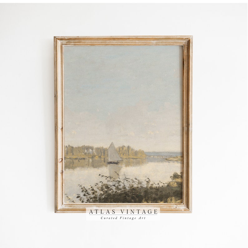 May include: A framed vintage painting of a sailboat on a lake with trees in the background. The sky is a light blue with some clouds. The painting is in a light wood frame.