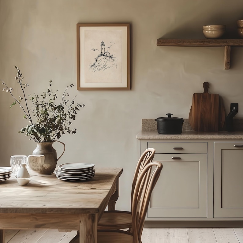May include: A dining room scene featuring a wooden table set with plates and a vase of greenery. A framed artwork of a lighthouse hangs on the wall. The room also includes a wooden shelf with bowls, a cutting board, and a black pot on the countertop.