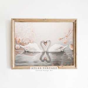 May include: A framed vintage print depicting two white swans with their necks intertwined in the shape of a heart. The swans are floating on a body of water with pink blossoms and leaves scattered on the surface. The background is a soft pink and peach colour.