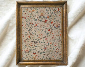 Könnte beinhalten: Ein gerahmter Vintage-Druck mit einem floralen Muster mit roten, blauen und grünen Blumen und Vögeln auf cremefarbenem Hintergrund. Der Rahmen ist golden und hat ein schlichtes Design. Der Text "ATLAS VINTAGE Curated Vintage Art" befindet sich oben im Bild.