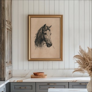 May include: A black and white drawing of a horse's head in a gold frame. The drawing is on a beige background.
