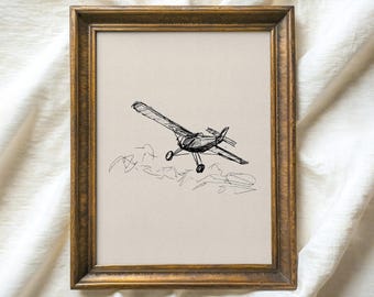 Pode incluir: Um desenho a preto e branco de um pequeno avião a voar sobre as nuvens. O desenho está emoldurado numa moldura dourada e tem o título "ATLAS VINTAGE Arte vintage selecionada".