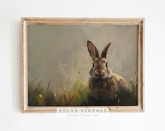 May include: A vintage painting of a brown rabbit sitting in a field of green grass. The rabbit is looking directly at the viewer with its ears perked up. The painting is framed in a light wood frame.
