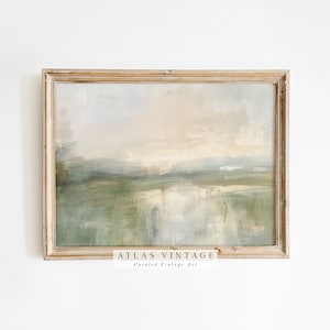 Può includere: Un dipinto astratto di paesaggio incorniciato in toni tenui di verde, blu e bianco. Il dipinto è in una cornice di legno chiaro e ha il testo "ATLAS VINTAGE Arte vintage selezionata" in basso.