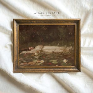 May include: A framed vintage art print depicting a woman in a white dress in a pond with water lilies. The artwork is in a gold-coloured ornate frame. The text "ATLAS VINTAGE" and "Curated Vintage Art" is visible at the top.