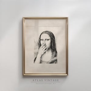 Pode incluir: Impressão emoldurada em preto e branco de Mona Lisa com o dedo no nariz. A obra de arte está em uma moldura dourada e apresenta o texto "ATLAS VINTAGE Curated Vintage Art" na parte inferior.