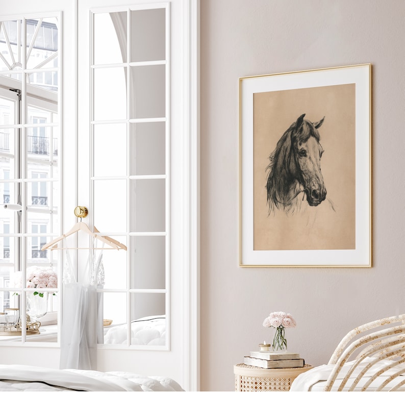 May include: A black and white drawing of a horse's head in a gold frame hanging on a light pink wall. The horse's head is facing to the right and the drawing is on a beige background.