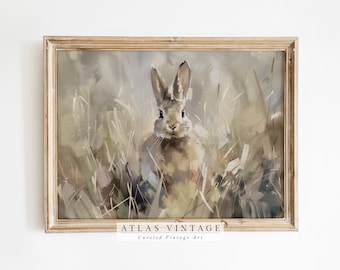 May include: A vintage painting of a brown rabbit sitting in tall grass. The rabbit is looking directly at the viewer. The painting is framed in a light wood frame. The text "ATLAS VINTAGE Curated Vintage Art" is at the bottom of the frame.