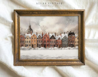 May include: A framed watercolor painting of a row of colorful houses in a snowy town. The houses have white trim and are lined up in a row. The sky is gray and there is snow falling. The painting is in a gold frame.