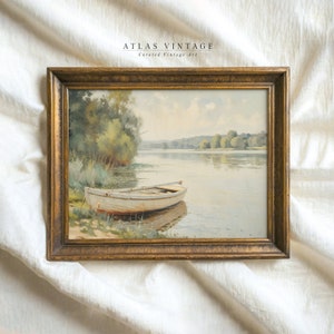 May include: A framed watercolor painting of a white boat on a lake. The boat is docked on the shore with green trees and bushes in the background. The sky is a light blue with white clouds. The painting is in a gold frame.