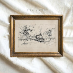 May include: A framed vintage art print featuring a black and white sketch of a steam train on tracks. The artwork is set in a gold-colored frame. The text "ATLAS VINTAGE" and "Curated Vintage Art" is visible at the top.