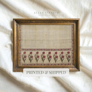 May include: A rectangular framed textile piece featuring a beige background with a repeating pattern of red tulips along the bottom border and sides. The frame is a dark metallic gold. The text ATLAS VINTAGE and PRINTED & SHIPPED are visible.