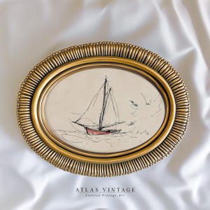 May include: An oval, gold-framed artwork featuring a sketch of a sailboat with a red hull. The artwork is set against a cream-colored background. The frame has a textured, ridged design. The text "ATLAS VINTAGE Curated Vintage Art" is at the bottom.