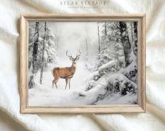 May include: A framed print of a winter scene with a deer standing in a snowy forest. The deer is brown with antlers and is looking to the right. The forest is covered in snow and the trees are bare. The print is in a light wood frame.