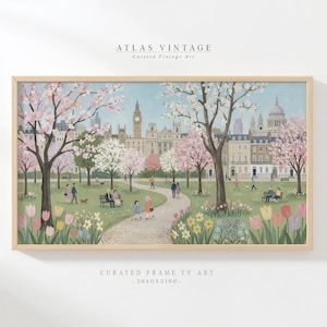 May include: A framed print depicting a park scene with cherry blossom trees, people, and buildings. The artwork features a light blue sky and a path winding through a green lawn with colorful flowers. The text "ATLAS VINTAGE" and "CURATED FRAME TV ART" are visible.