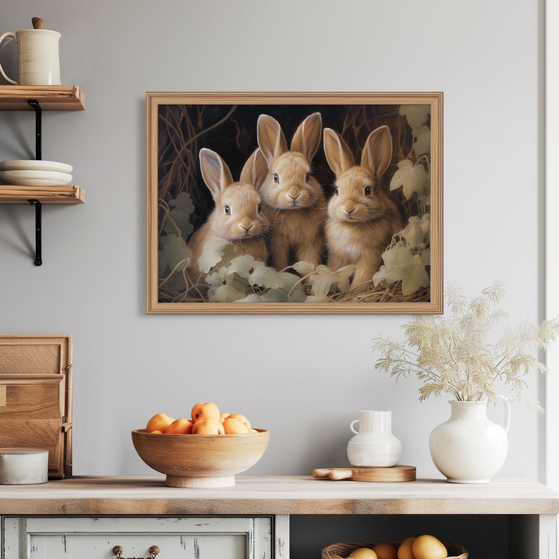 Pu&ograve; includere: Una stampa incorniciata con tre adorabili conigli marroni raggruppati. L'opera d'arte ha una calda tavolozza di colori con luci soffuse e dettagli. I conigli sono circondati da fogliame, creando una scena naturale e accogliente. La cornice &egrave; di colore legno chiaro.