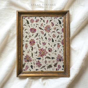 May include: A framed vintage print with a floral pattern in shades of pink, red, and green on a white background. The frame is gold and has a simple design.
