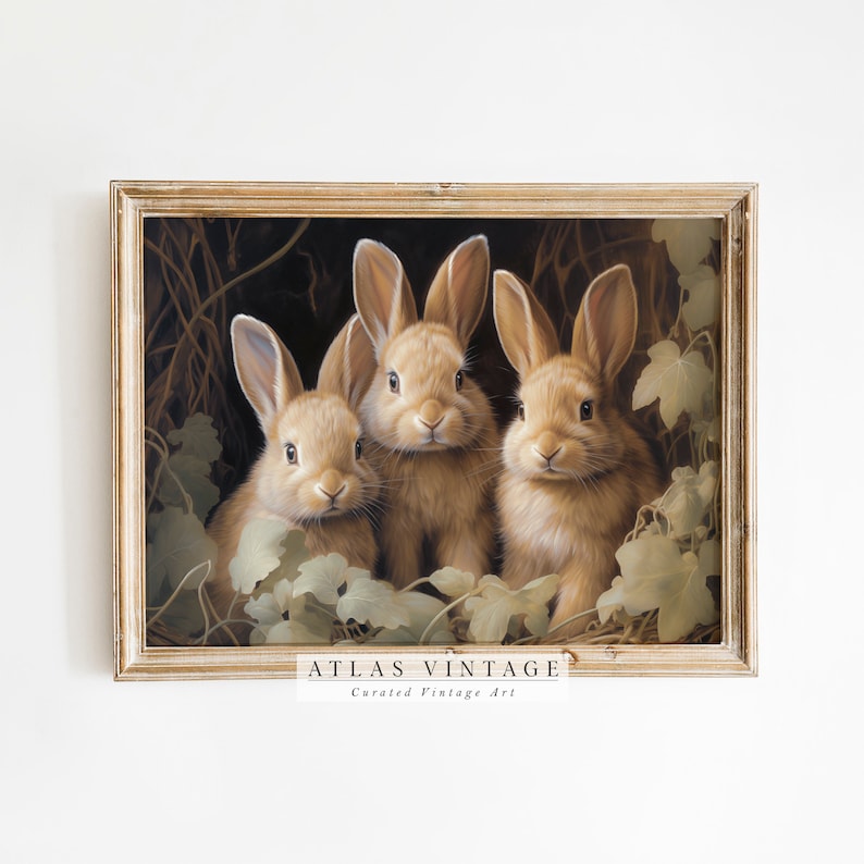 Pu&ograve; includere: Una stampa vintage incorniciata con tre conigli marrone chiaro tra il fogliame. L'opera d'arte ha una calda tavolozza di colori e una cornice dorata. Il testo "ATLAS VINTAGE Curated Vintage Art" &egrave; in basso.